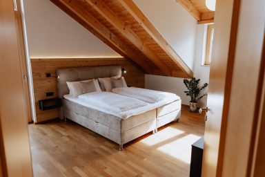 Helles Schlafzimmer mit Holzschnittholzdecken, Bett und Pflanzen.