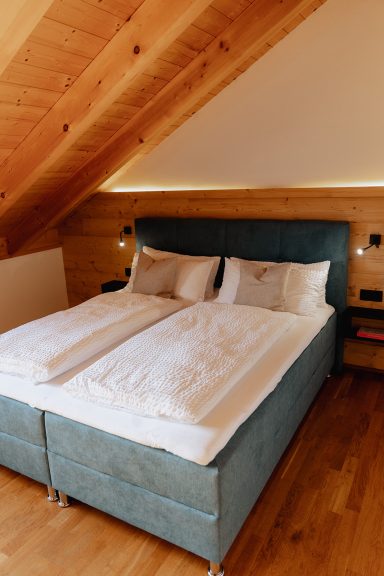 Helles Schlafzimmer mit einem Doppelbett und Holzdecken, gemütlich eingerichtet.