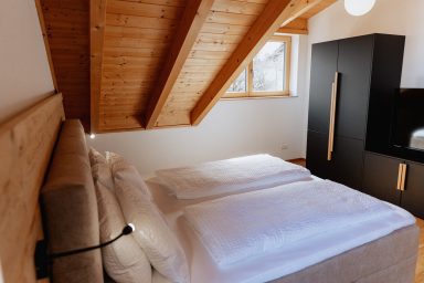 Helle, gemütliche Dachgeschoss-Schlafzimmer mit Holzdecke und modernen Möbeln.