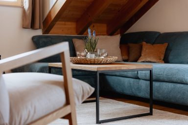 Gemütliche Sitzecke mit einem grünen Sofa, Holztisch und Kissen auf dem Sofa.