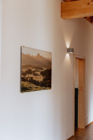 Landschaftsmotiv mit Bergen und Tal, aufgehängt an einer hellen Wand.