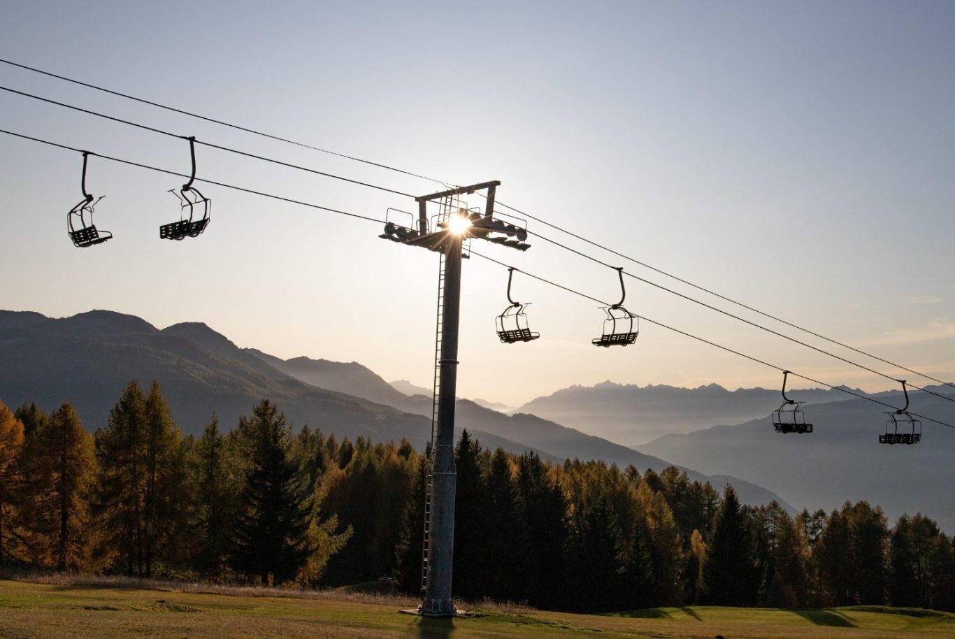 Seilbahn mit Bergen Eine Seilbahn schwebt über grüne Wälder und Berge unter blauem Himmel.