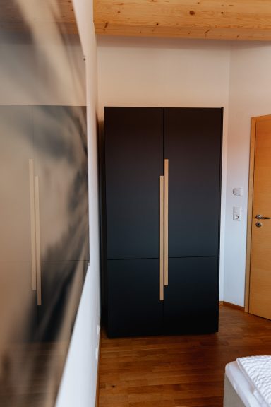 Moderne schwarze Kommode mit Griffleiste aus Holz in einem hellen Raum.
