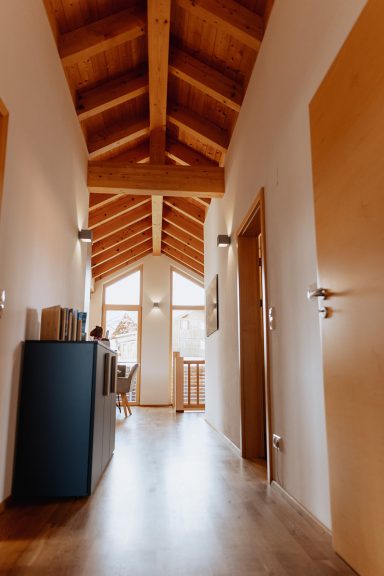 Heller Flur mit Holzbalkendecke und Türen zu verschiedenen Räumen.